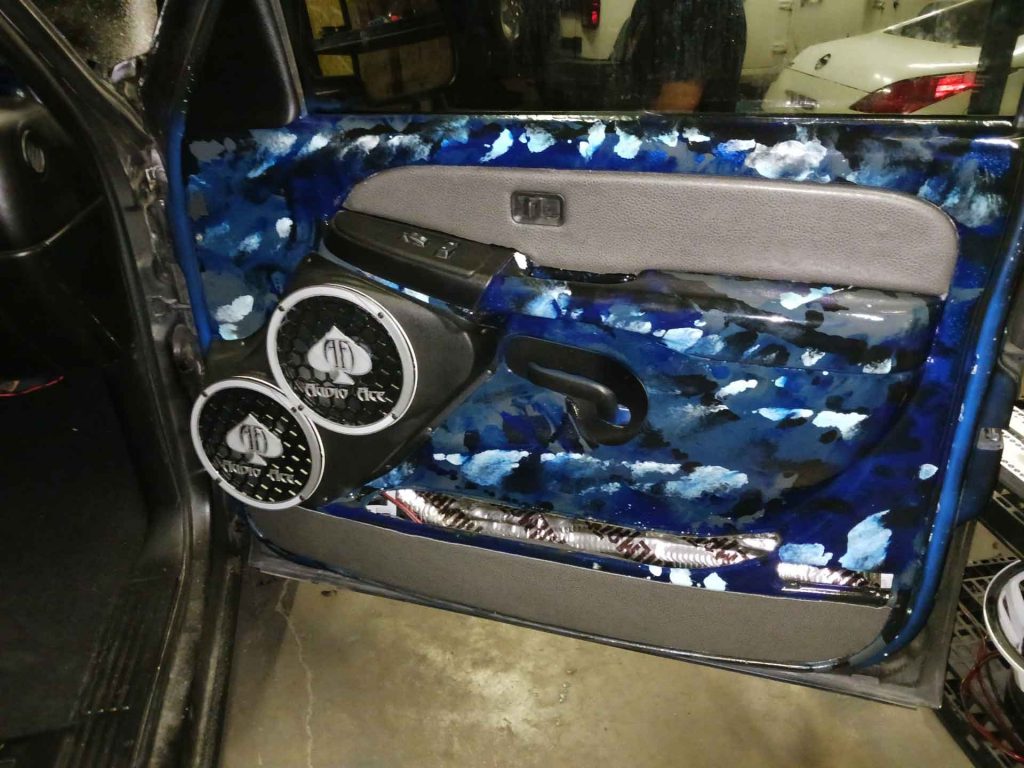Car door with marbled blue interior paint and two large speakers with the Audio Ace logo
